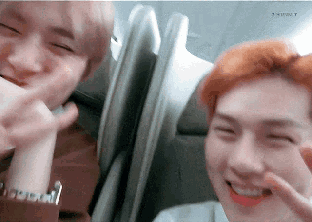 two young men are sitting next to each other on an airplane .