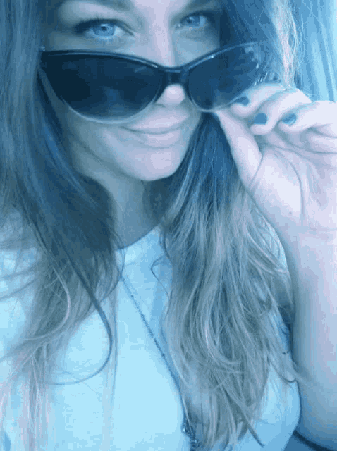 a woman wearing sunglasses is smiling and covering her face