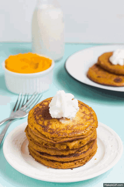 a stack of pancakes on a plate with whipped cream on top