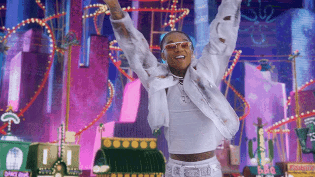 a man wearing sunglasses and a white jacket is standing in front of a roller coaster ..