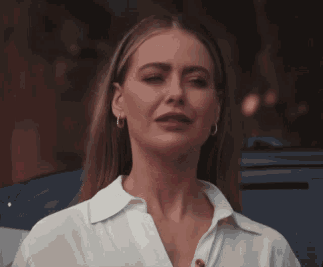 a woman wearing a white shirt and hoop earrings