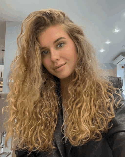 a woman with long curly blonde hair and blue eyes