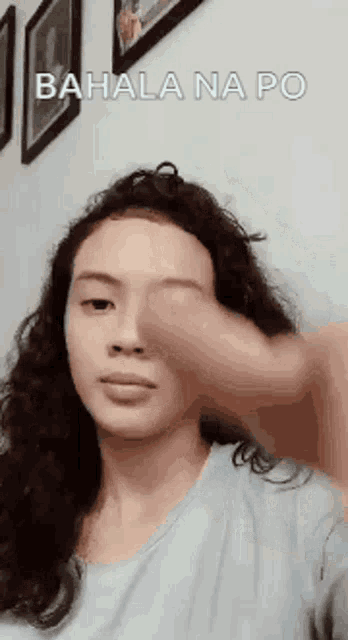 a woman with curly hair is making a funny face with her hand on her face .