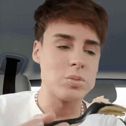 a young man in a white shirt is holding a black spoon