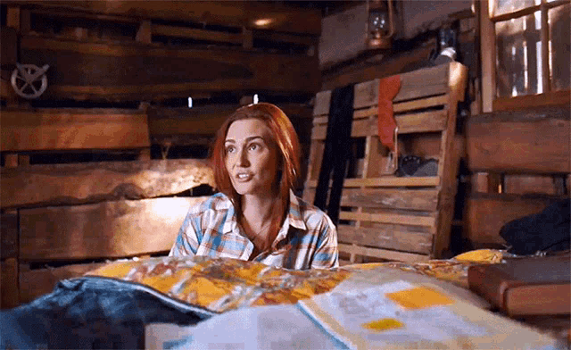a woman with red hair is laying on a bed in a wooden cabin