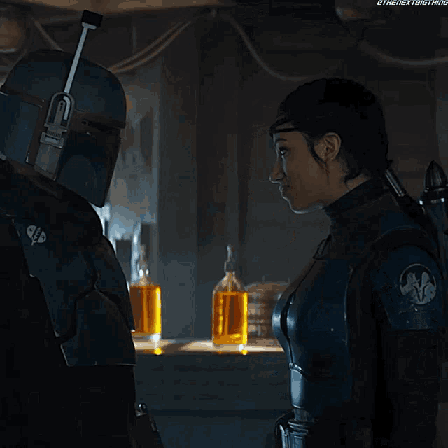 a man and a woman are looking at each other in a dark room with bottles of alcohol behind them