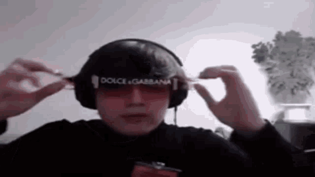 a man wearing headphones and sunglasses is holding a pair of sunglasses in his hands .