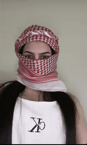 a woman wearing a red and white scarf around her face and a white shirt with the letters ck on it