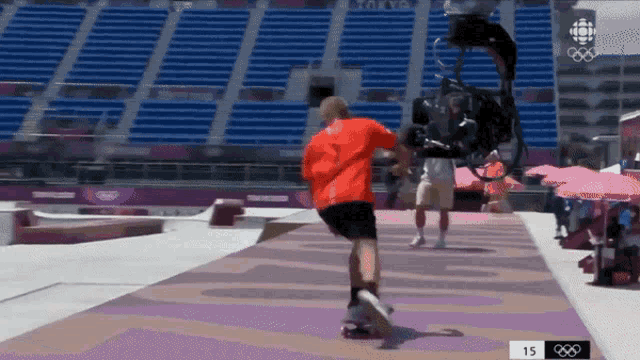 a skateboarder is being filmed by a camera while wearing a red shirt that says tokyo