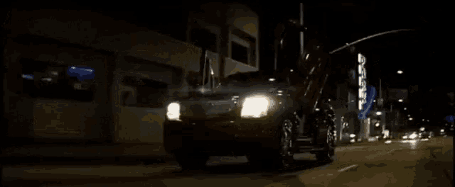 a car is driving down a street at night with a building in the background