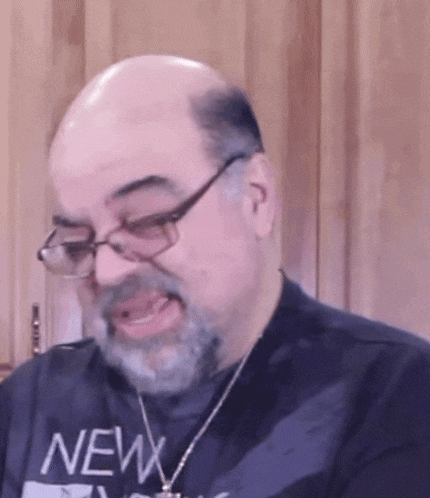 a bald man with glasses and a beard is wearing a shirt that says new york on it .