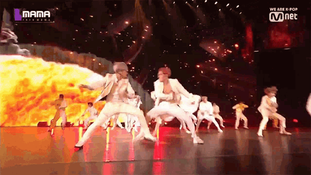 a group of people are dancing on a stage in front of a large screen that says mama