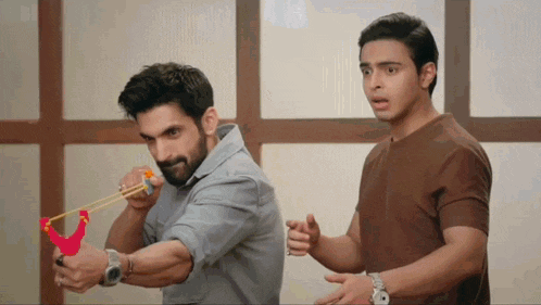 a man is holding a slingshot while another man looks on