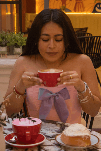 a woman sitting at a table with a cup of coffee and a piece of cake