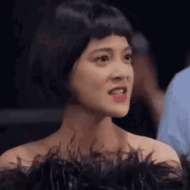 a close up of a woman wearing a feathered top and a wig .