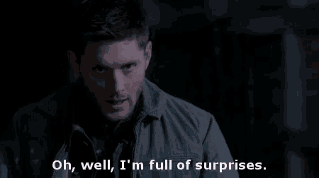 a man is standing in a dark room and talking about surprises .