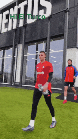 a man in a red shirt is walking in front of a building that says juventus