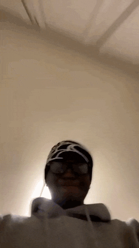 a person wearing a hat and glasses is taking a selfie .