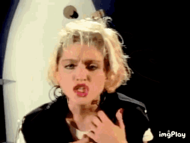 a woman with blonde hair and red nails is making a funny face with her mouth open .
