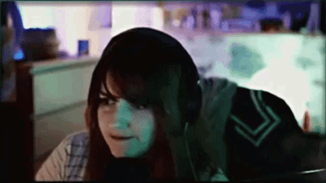 a woman wearing headphones and a hoodie looks at the camera .