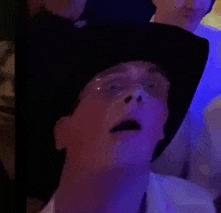 a man wearing a cowboy hat and glasses is looking up at something