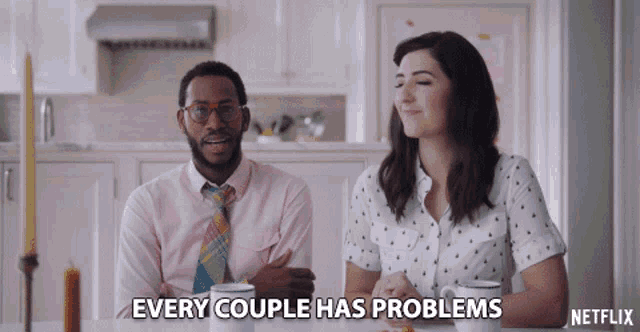 a man and a woman sit at a table with the words " every couple has problems " written on the table