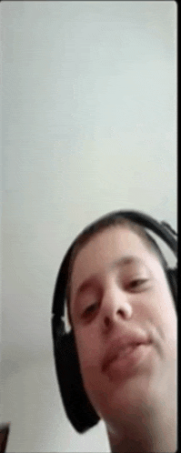 a man wearing headphones is taking a selfie with his phone .
