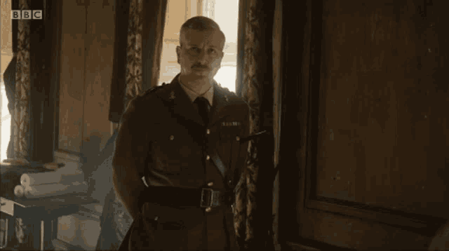 a man in a military uniform is standing in a room with bbc written on the screen