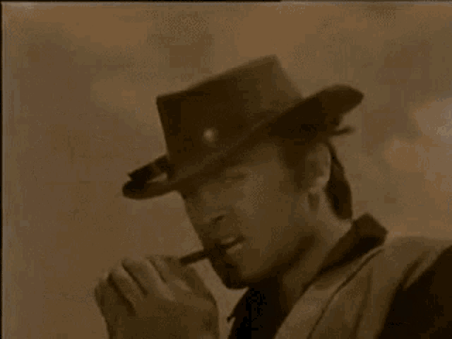 a man in a cowboy hat is standing in front of a group of men and a horse .