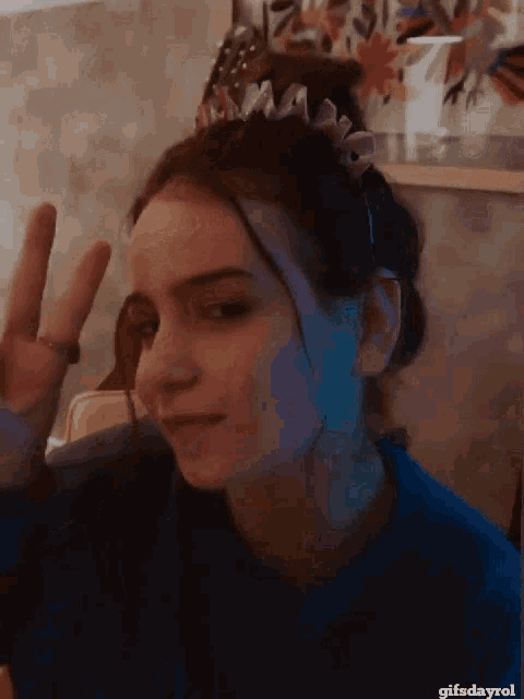 a girl with a crown on her head is giving the peace sign