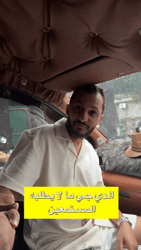 a man in a white shirt sits in a car with a yellow sign that says ' a ' on it