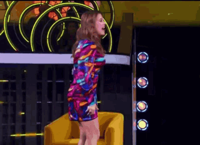 a woman in a colorful dress sits in a yellow chair