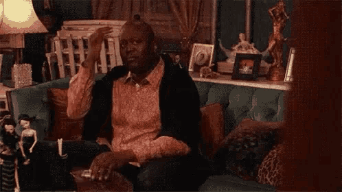 a man is sitting on a couch smoking a cigarette