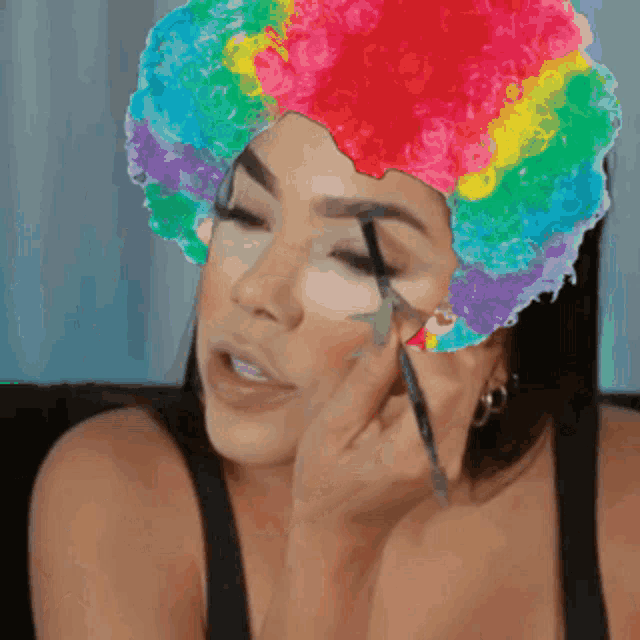 a woman wearing a clown hat is applying makeup