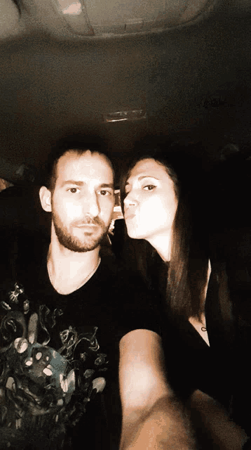 a woman blowing a kiss on a man 's cheek in a car