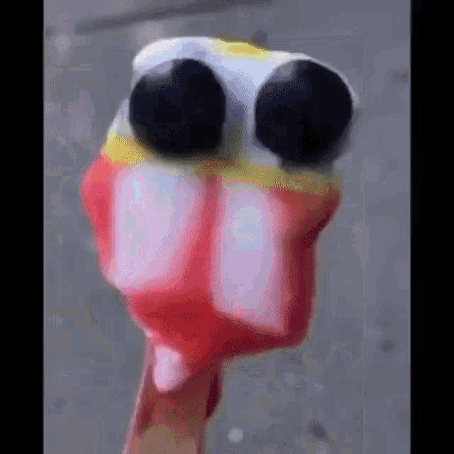 a close up of a person holding an ice cream cone with a face on it .