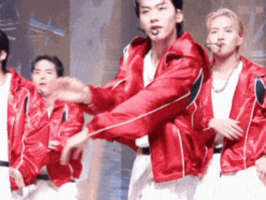 a group of young men wearing red jackets are performing on stage