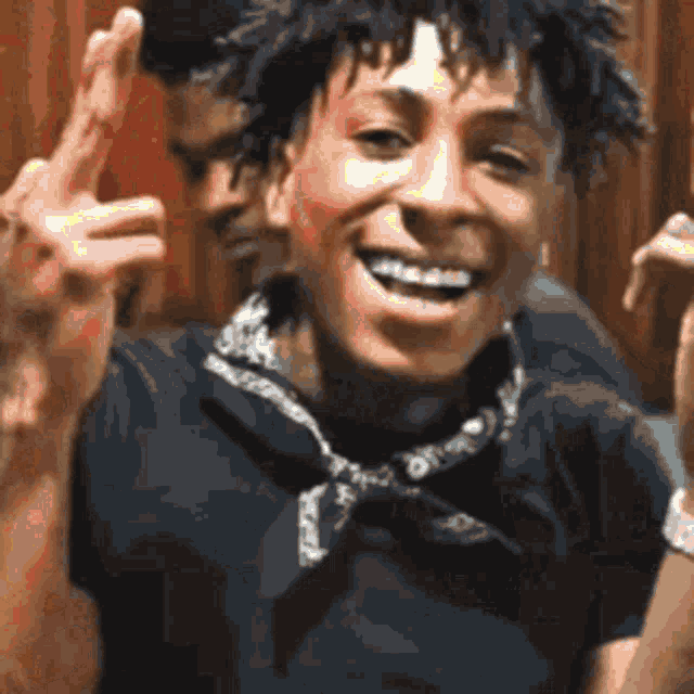 a young man is giving the middle finger and smiling while wearing a bandana .