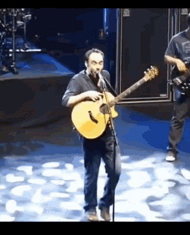 a man playing a guitar and singing into a microphone