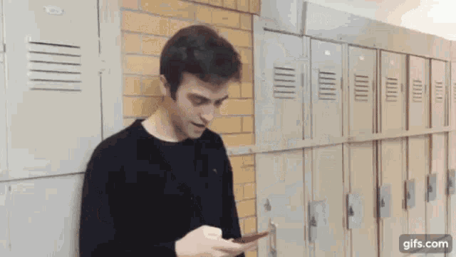 a man is standing in front of a row of lockers holding a card .