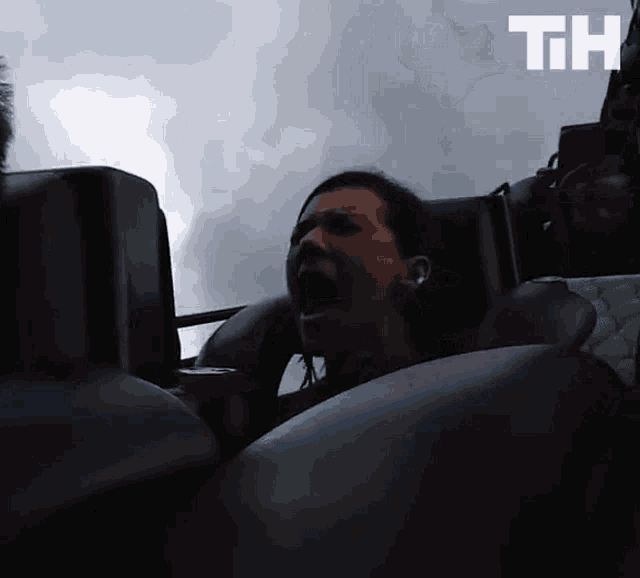 a woman is crying while riding a roller coaster with the letters th above her head