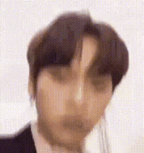 a man in a suit and tie is making a funny face while looking at the camera .