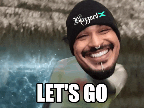 a man with a beard wearing a blizzard hat is smiling and says let 's go