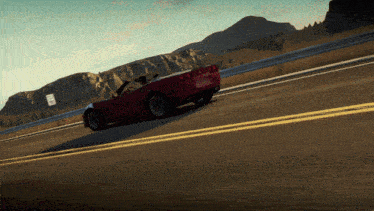 a red car is driving down a road with mountains in the background and a sign that says no parking