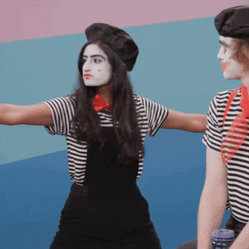 a woman in a black and white striped shirt is standing next to a man in a mime costume