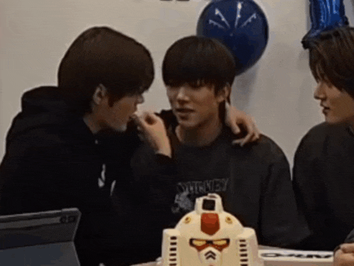 a group of young men sitting around a table with a robot cake on it