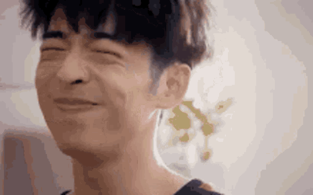 a young man is smiling with his eyes closed .