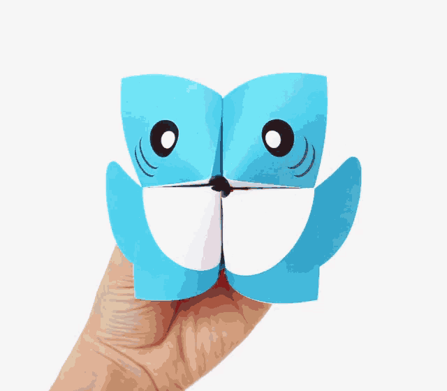 a hand is holding a blue and white origami shark