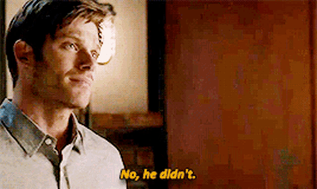 a man says no , he didn 't while standing in front of a wooden door .