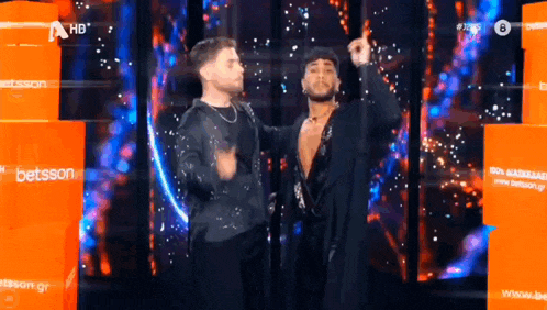 two men are dancing on a stage in front of a betsson sign .